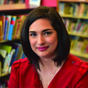 woman wearing a red blouse in front two bookcases