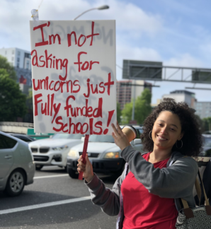 A woman hoists a sign at OEA’s Day of Action