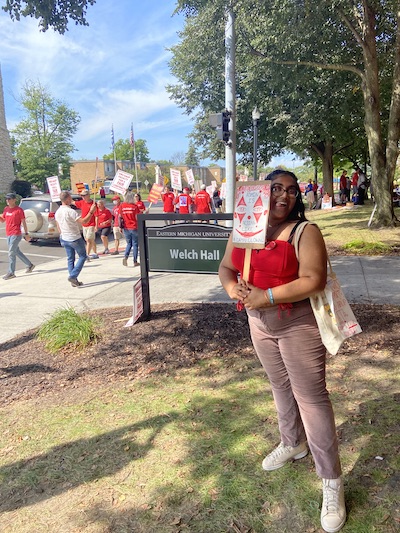 Photo of aspiring educator, holding a sign, during a campus protest