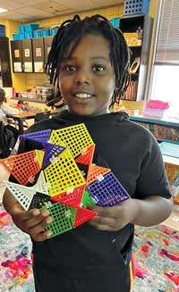 Young black male smiling with his HyperTiles toy.