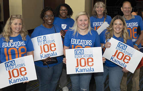 NEA members hold Educators for Joe and Kamala signs outside of rally