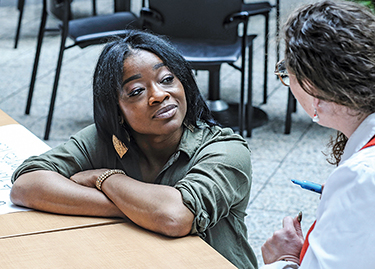 Katie Fuller sits at a table and talk with an educator colleague