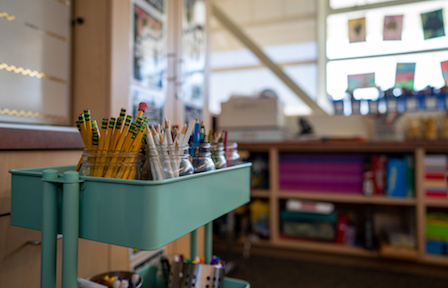 Cart and shelves in classroom with organized school supplies