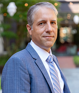 Derek W. Black portrait standing outside, blurred trees behind him.