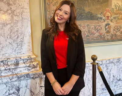 A female smiling and posing in front of a decorative background.  