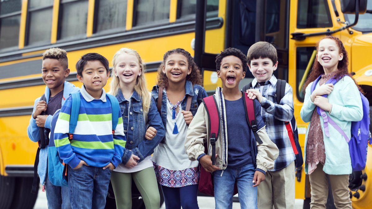 elementary students standing in front a school bus