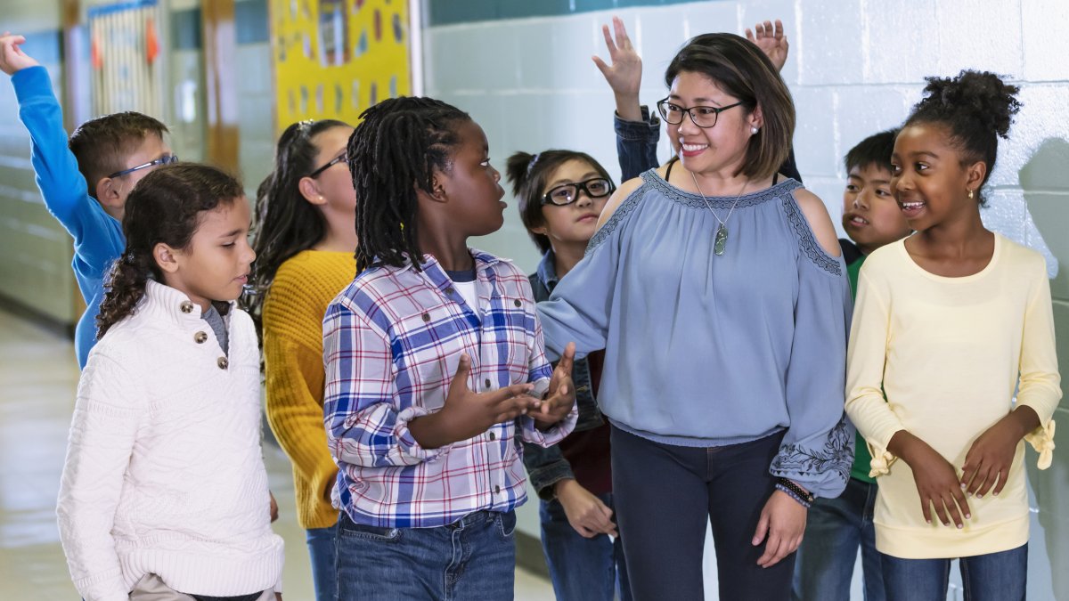 teacher walking down a school hallway with a group of diverse middle school students