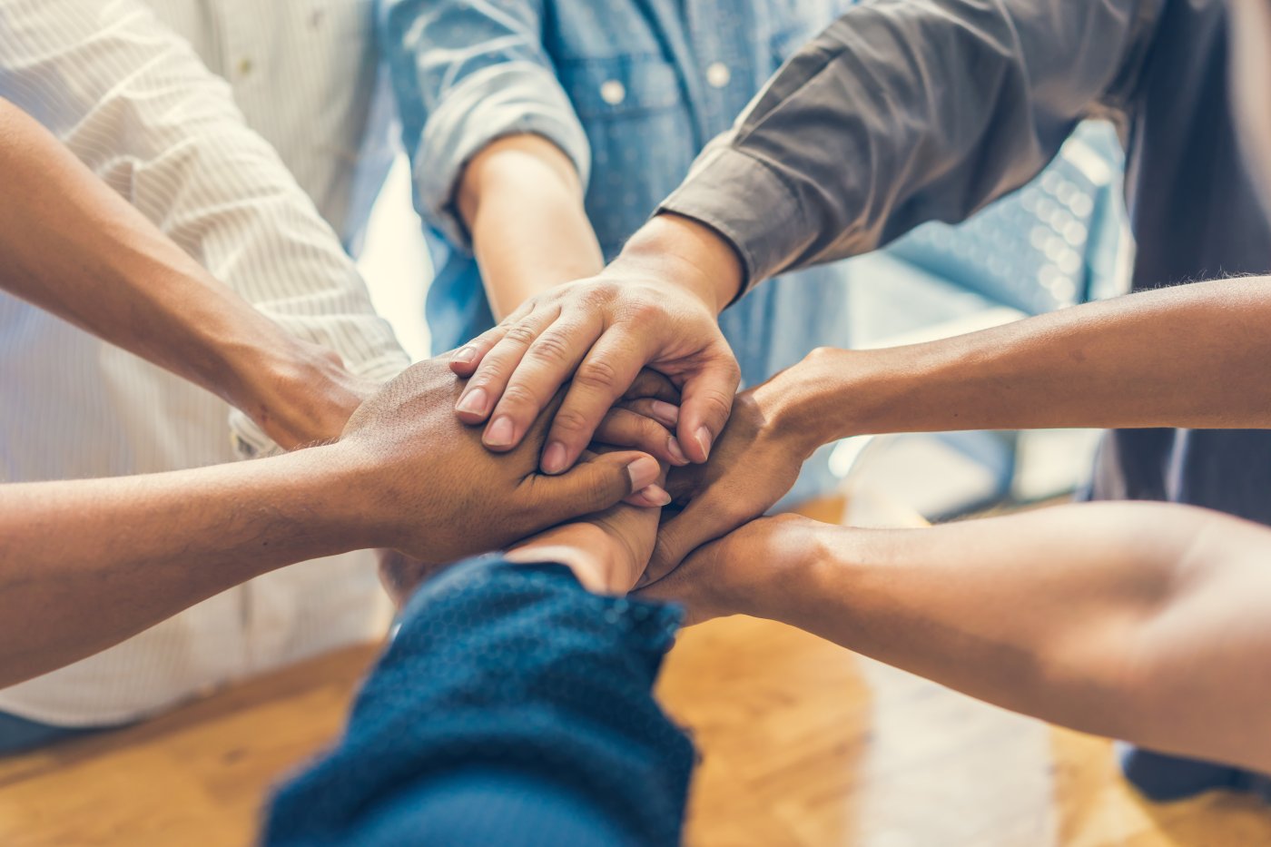 Close up of a group of stacked hands from people reaching into a circle