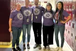 5 teachers wearing matching purple pro-union t-shirts stand in a school hallway lined with lockers