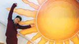 student posing with school mural