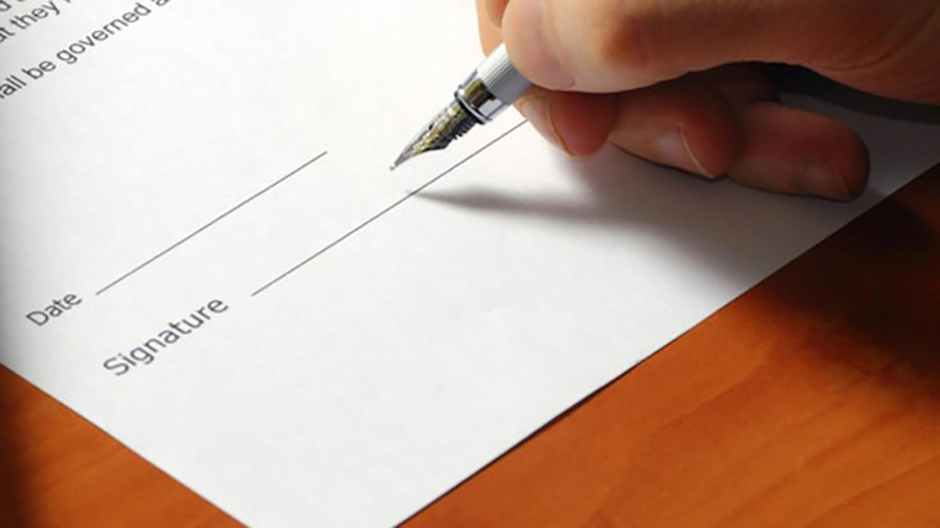 A close-up shot of a hand signing a contract