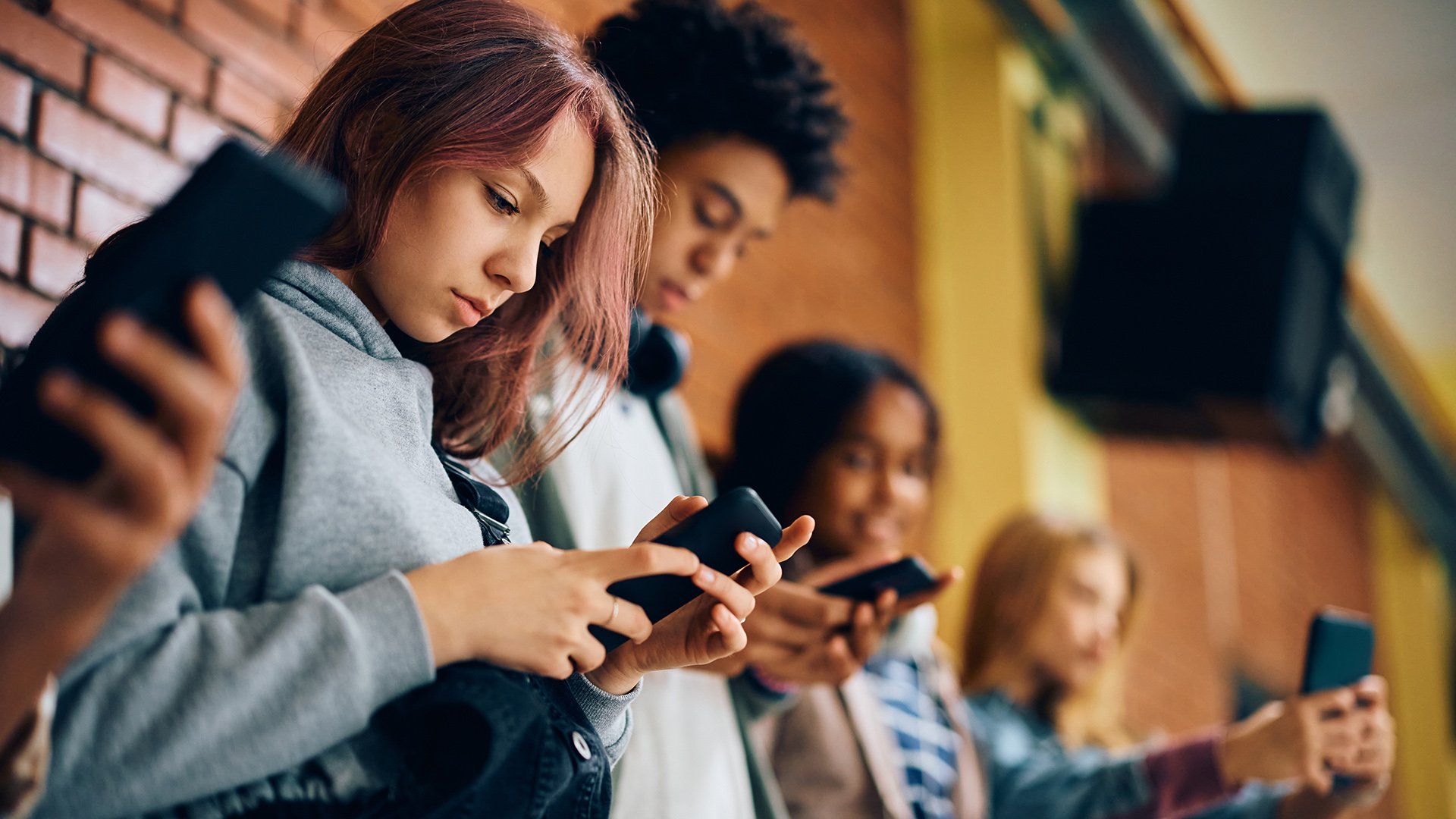 Students in school hallway looking at their cell phones