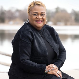 educator Brenda Johnson sits outside in front of a lake