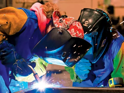 High school students Daisy Massey and Erica Lopez weld metal together.