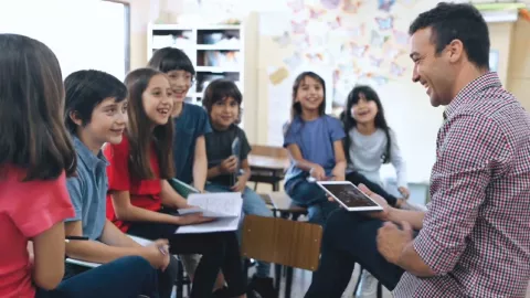 Caucasian Male teacher with students smiling.