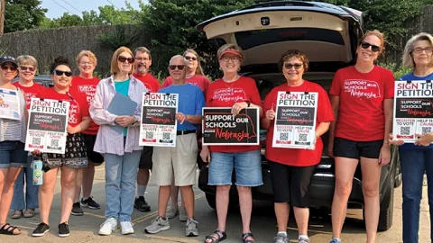 Nebraska members holding up signs - Support Our Schools and Sign the Petition