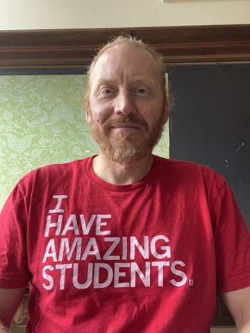 Male teacher, smiling, wearing red-shirt that says, "I have amazing students."