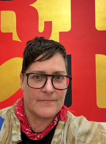 Kate Okeson poses in front of red and yellow back drop.