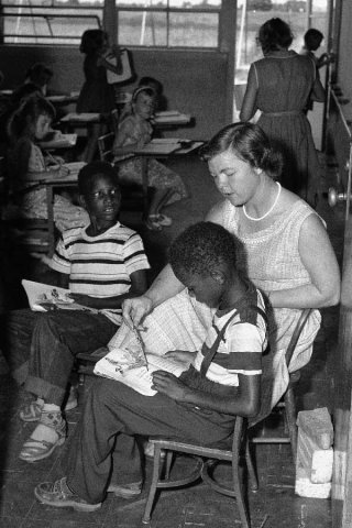 Black and white image of classroom with 23 black students and a white female teacher.