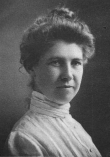 An old black and white photograph featuring a woman elegantly dressed in a white gown.