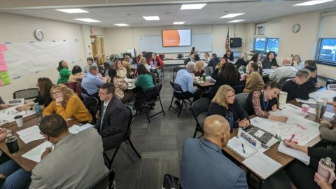 educators and administrators work in groups at tables as part of NJEA's labor management collaborative