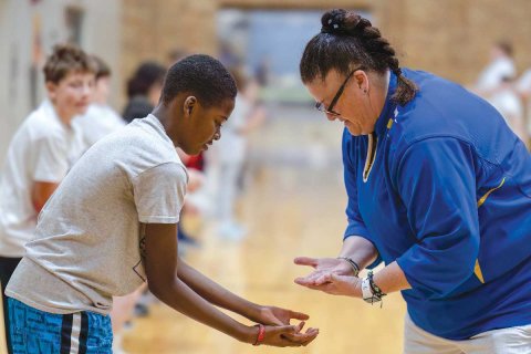 Sheila Patterson working with a Black male student on hand exercises.