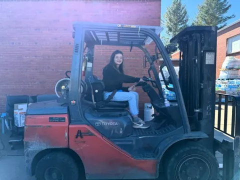 Educator learns to use a forklift as she organizes distribution center